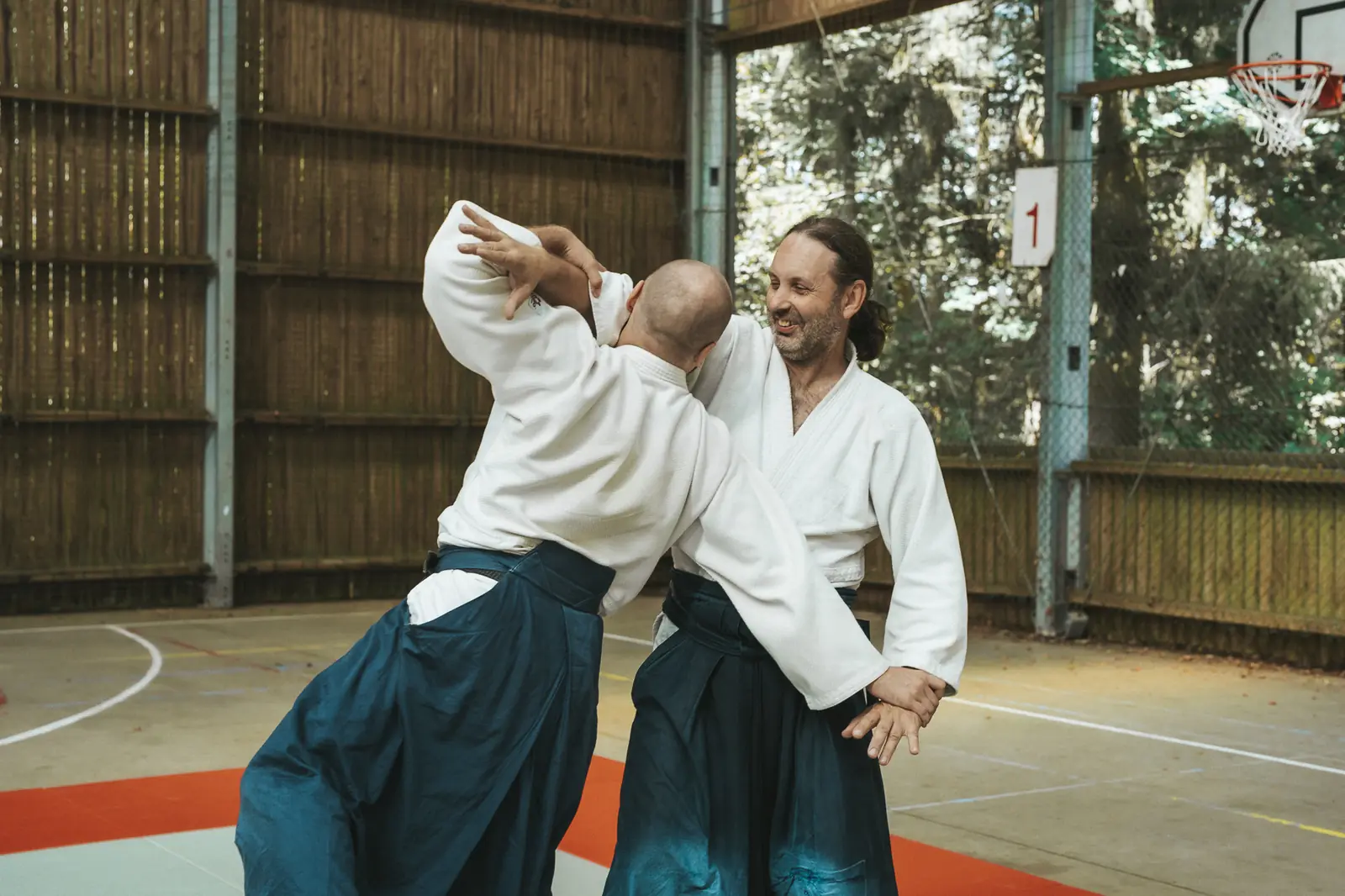 Le professeur accompagne un partenaire dans une projection au dojo