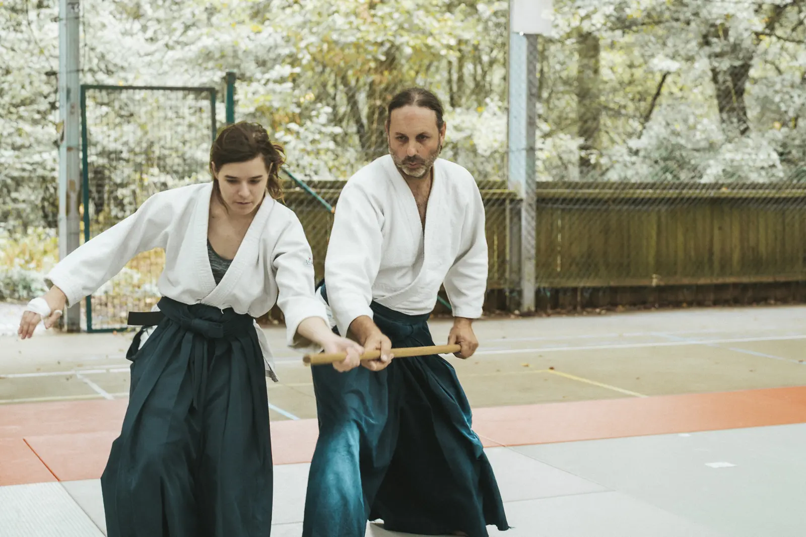 Deux pratiquants, une femme et un homme, s’exercent au bokken en extérieur