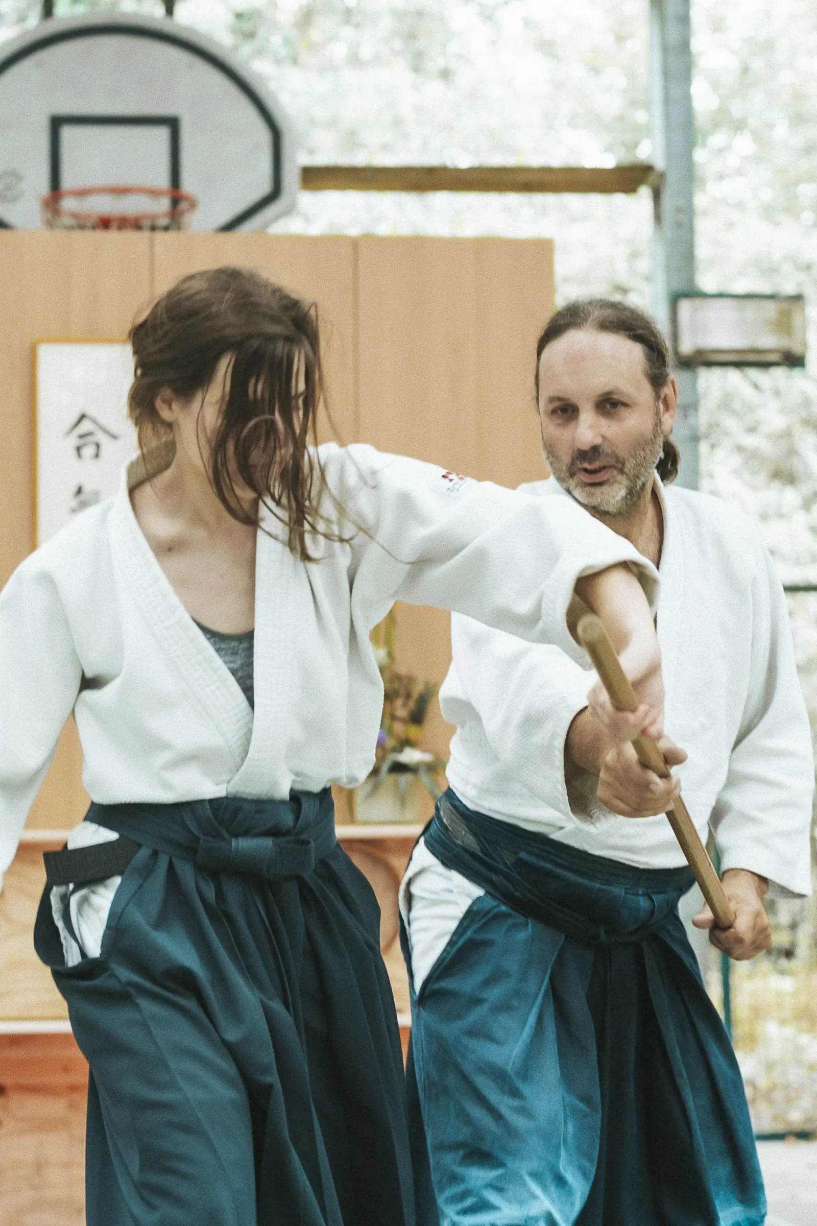 Deux pratiquants, bokken et jo en main, s’entraînent face à face