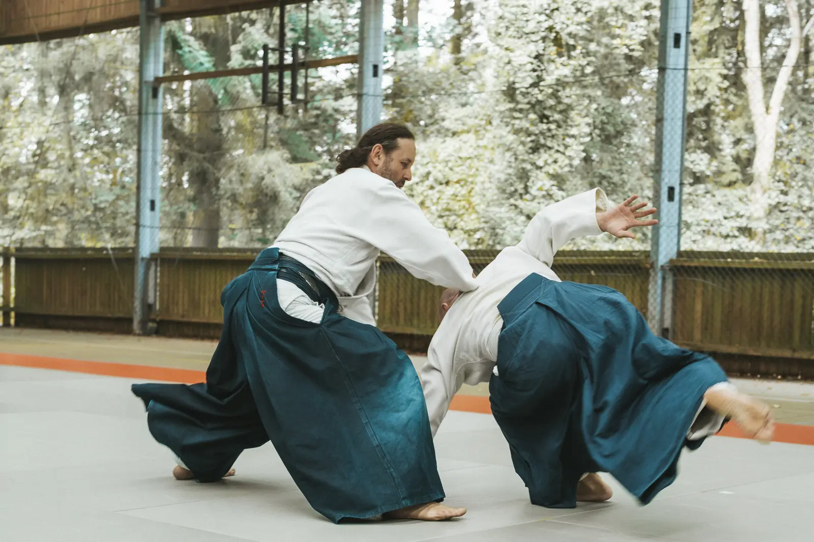 Deux pratiquants enchaînent une projection dans la salle du dojo